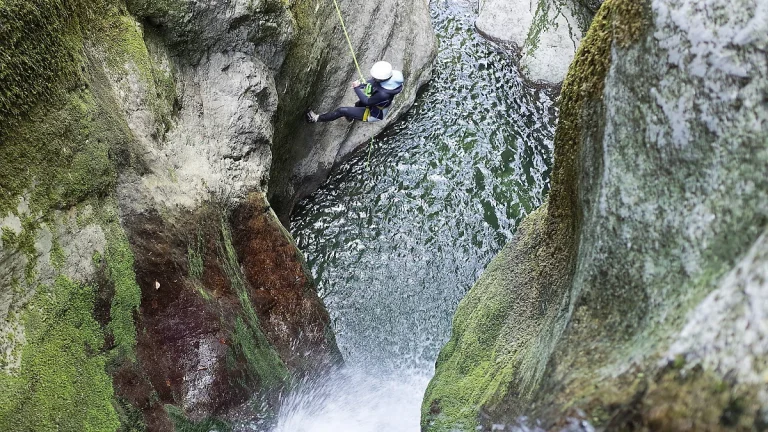 Descente en rappel dans une vasque d'eau turquoise en canyoning aux gorges du Flumen dans le Jura.