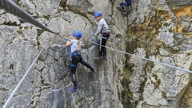 Les enfants traversent le pont Népalais du parcours ludique de la via ferrata de Morez dans le Jura.