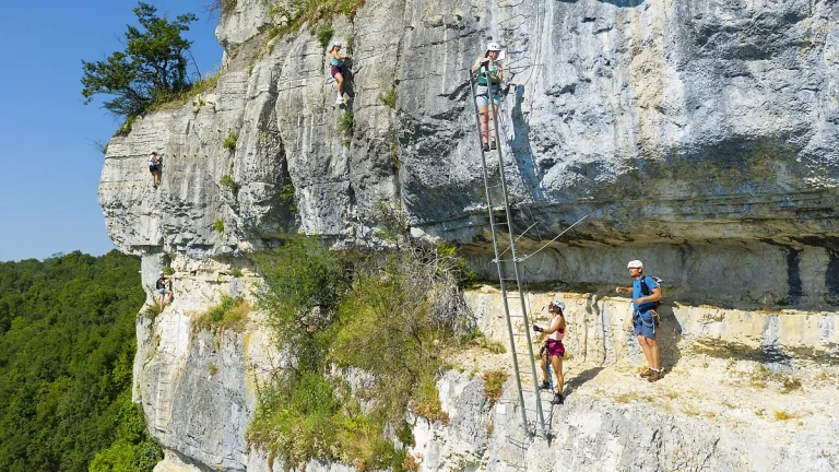 Escalade des échelles face au lac de Vouglans à la via ferrata du Regardoir de Moirans-en-Montagne dans le Jura.