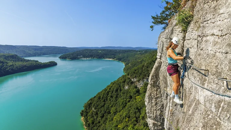 Traversée avec vue sur le lac de Vouglans sur la variante aérienne du parcours de la via ferrata du Regardoir à Moirans-en-Montagne dans le Jura.