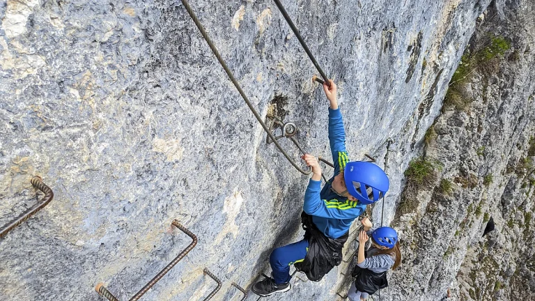 Passage d'escalade vertical sur le parcours de la via ferrata de la Roche au Dade de Morez dans le Jura.