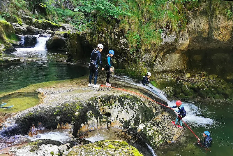 Une famille avec un enfant de 8 ans fait du canyoning dans le Jura. Les enfants s'amusent à glisser en tobogan avec la possibilité de remonter plusieurs fois.